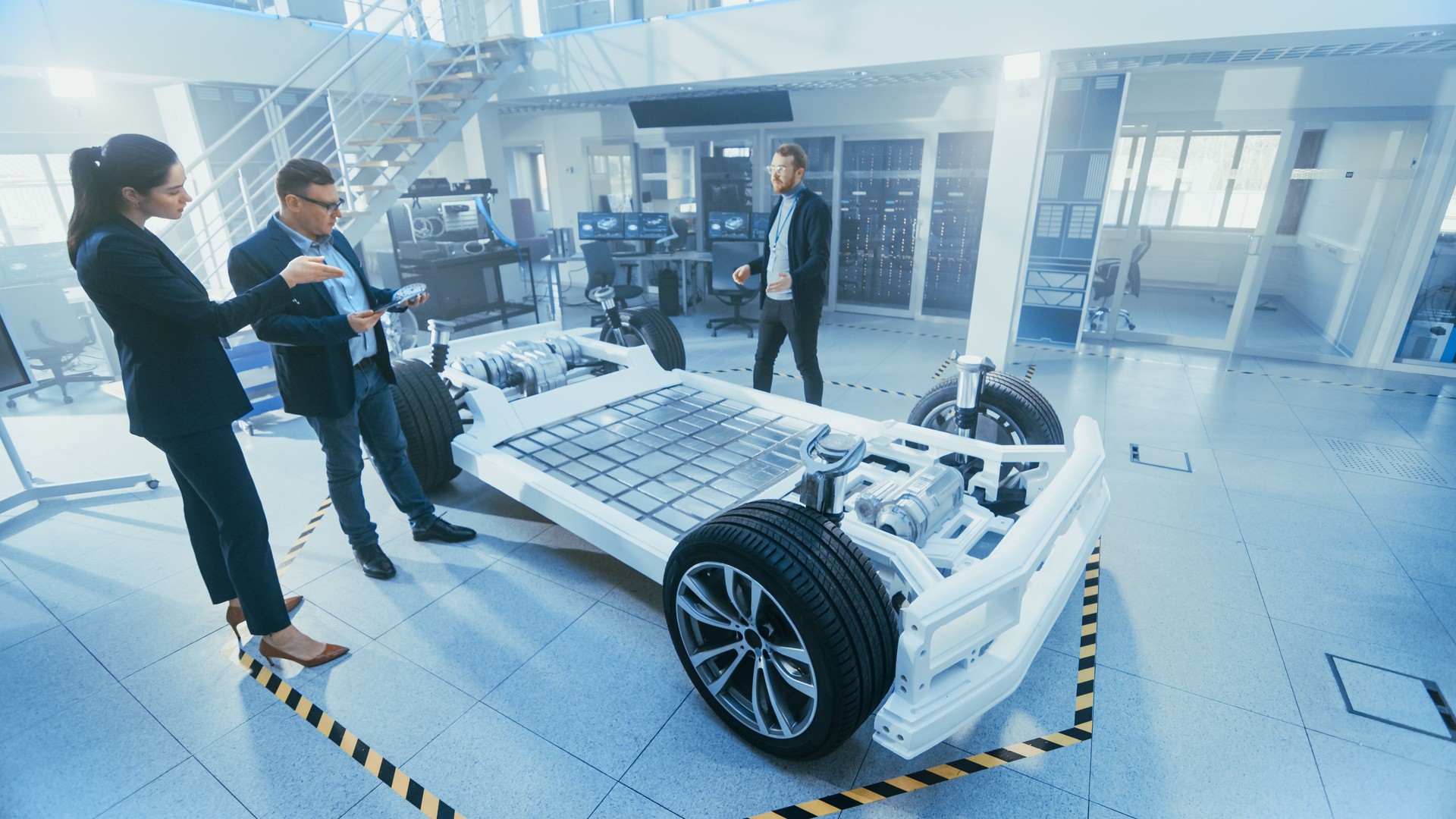 Automotive Design Engineer zeigt den Vertreter des Vorstands den Elektroauto-Chassis-Prototyp. Konzept inklusive Wheels, Hybrid Engine und Batterie.